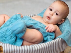 Imagem de um bebê aconchegado em um cobertor azul dentro de uma cesta Imagem de um bebê aconchegado em um cobertor azul dentro de uma cesta