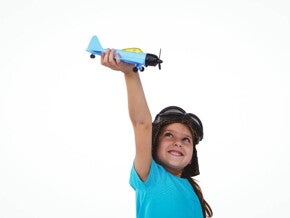 Menina sorrindo e segurando um avião de brinquedo acima da sua cabeça