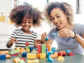 Mãe e filha brincam com blocos de montar para favorecer o desenvolvimento infantil