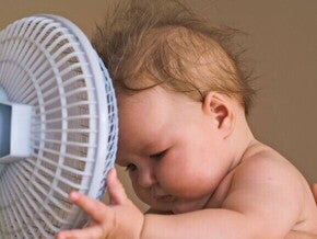 Um bebê com a cabeça próxima a um pequeno ventilador