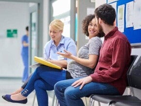 Gestante conversando com médico e acompanhante em hospital