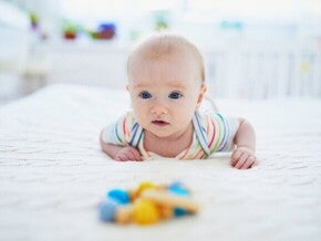 Um bebê deitado de barriga para baixo na cama, praticando tummy time, enquanto veste um body colorido.