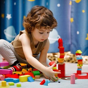 Neuroatípico: o que é e quais são os sinais nas crianças Criança brincando com blocos no chão