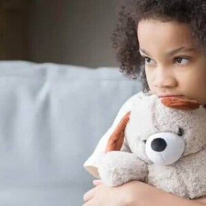 Aspeger Imagem de uma criança sozinha segurando um bicho de pelúcia, olhando de forma distraída para o nada, este olhar pode ser um sintoma de síndrome de asperger