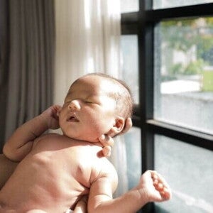 Bebê tomando banho de sol através da luz de uma janela