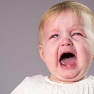 Um bebê chorando com a boca aberta, sobre um fundo lilás.