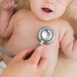 Um bebê deitado sendo examinado por um estetoscópio