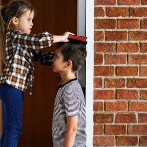 Duas crianças em frente um parede de tijolos brincando de medir a altura Duas crianças em frente um parede de tijolos brincando de medir a altura
