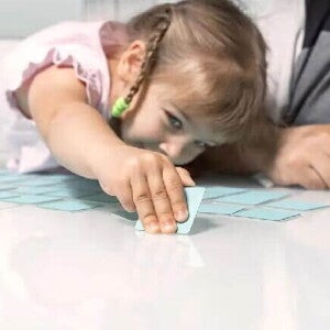 Jogos educativos Uma menina e um adulto brincam de jogo de memória, um dos tipos de jogos educativos.