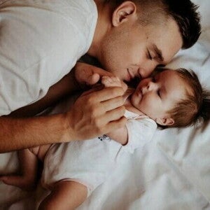 Homem deitado com um bebê em uma cama. Homem deitado com um bebê em uma cama.