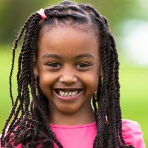 Close-up de uma menina sorrindo amplamente ao ar livre, ilustrando a beleza e a cultura dos nomes africanos femininos.