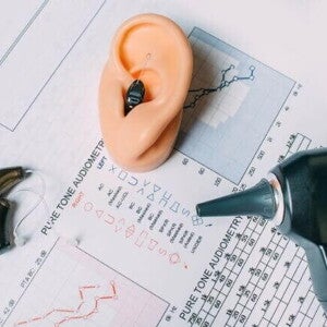 Diversos aparelhos voltados à saúde auditiva, dispostos em cima de um resultado de exame de audiometria Diversos aparelhos voltados à saúde auditiva, dispostos em cima de um resultado de exame de audiometria