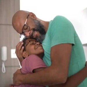 O que é parentalidade? Estamos fazendo do jeito certo? Exercendo a parentalidade positiva, pai abraça filho, dentro de casa.