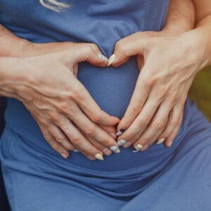 Casal com as mãos formando um coração em cima da barriga de grávida Casal com as mãos formando um coração em cima da barriga de grávida