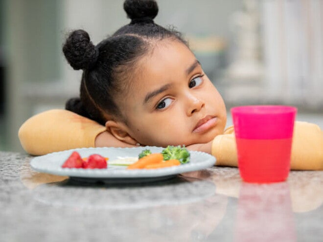 menina com semblante desconfiado olha para prato de comida sem vontade menina com semblante desconfiado olha para prato de comida sem vontade