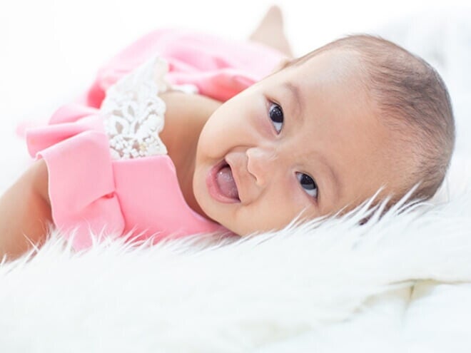 Imagem de bebê recém nascido usando vestido rosa e deitada em uma cama de lençóis brancos. Imagem de bebê recém nascido usando vestido rosa e deitada em uma cama de lençóis brancos.