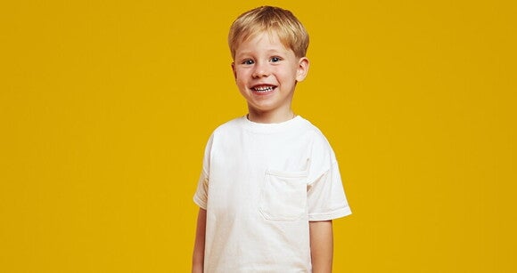 Menino loiro vestindo camiseta branca e sorrindo
